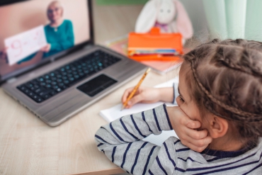 Una niña se concentró en su computadora portátil mientras estaba sentada en un escritorio.